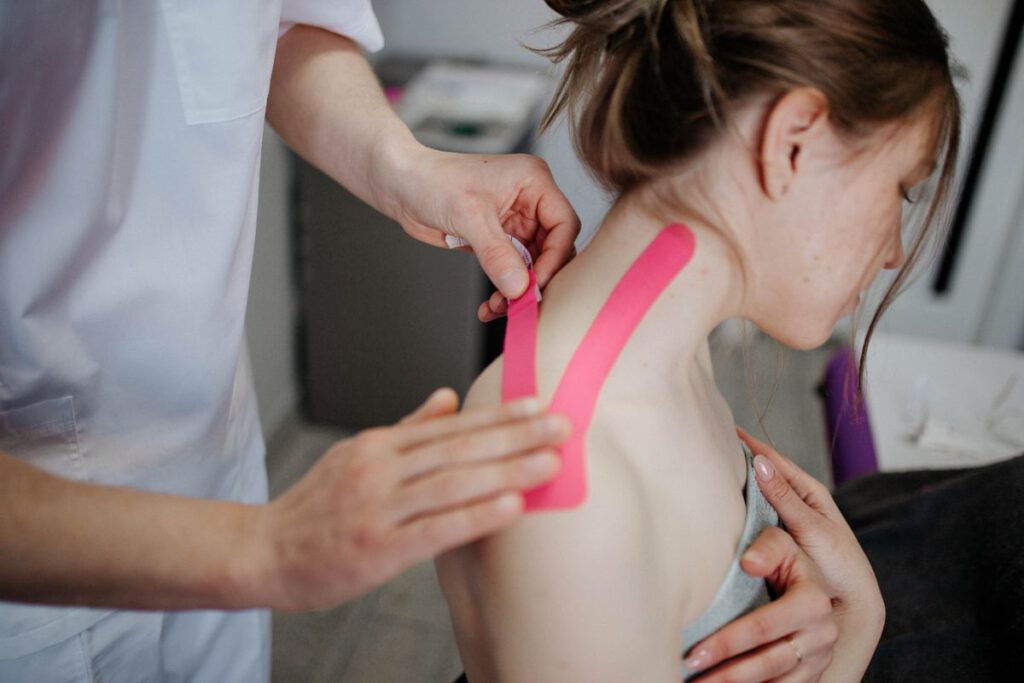 Fysiotherapeut brengt kinesiotape aan op een schouder